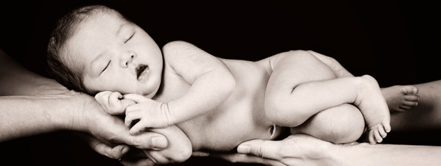 Newborn baby being held by both parents hands